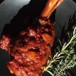 Moroccan lamb shank on a black plate.