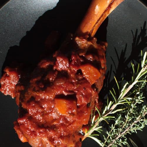 Moroccan lamb shank on a black plate.