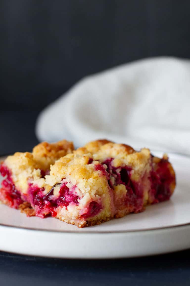 A piece of German plum coffee cake on a white plate.