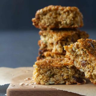 Five chewy granola bars on baking paper and a wooden board.