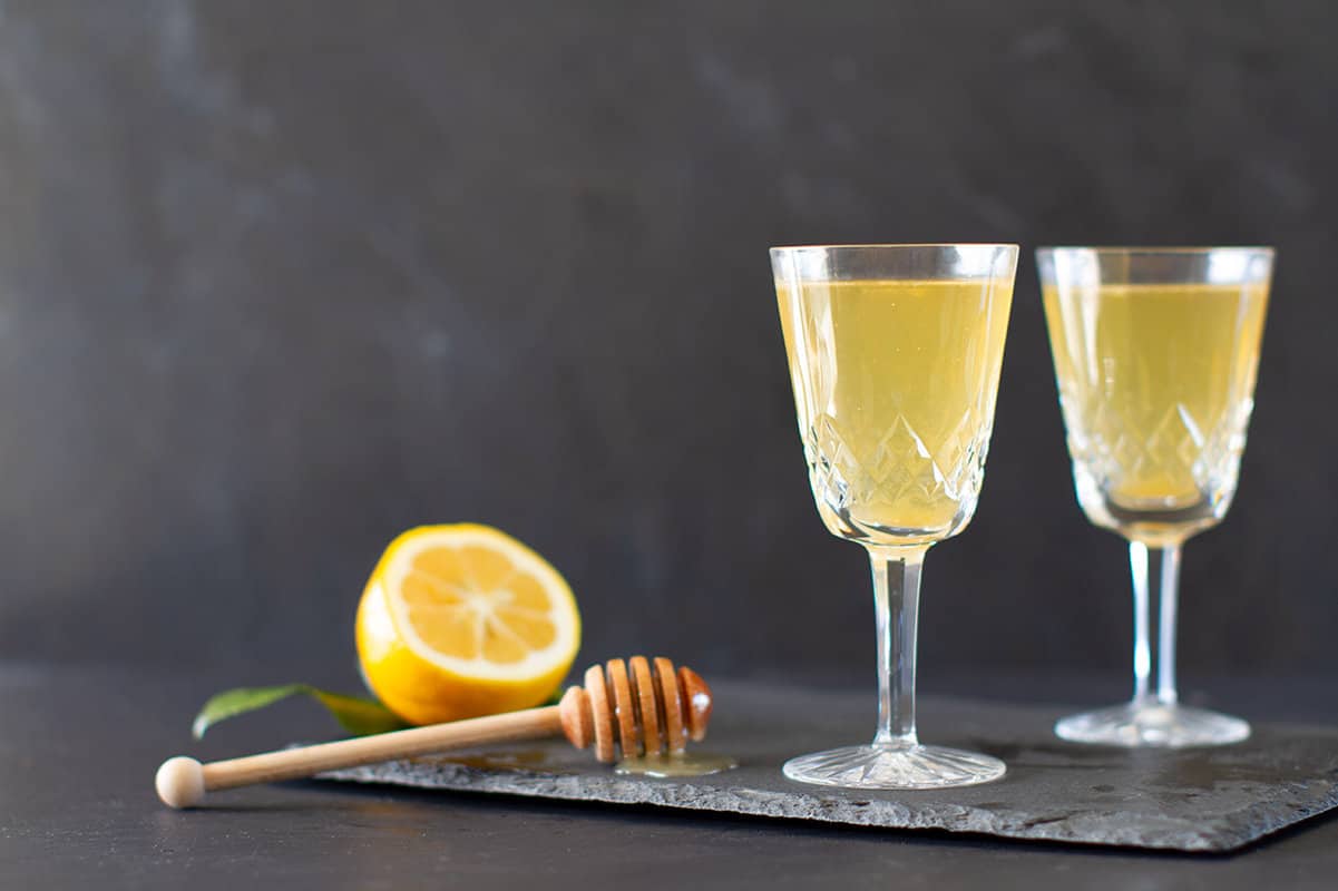 Two vintage wine glasses with lemonade on a black shingle tile.