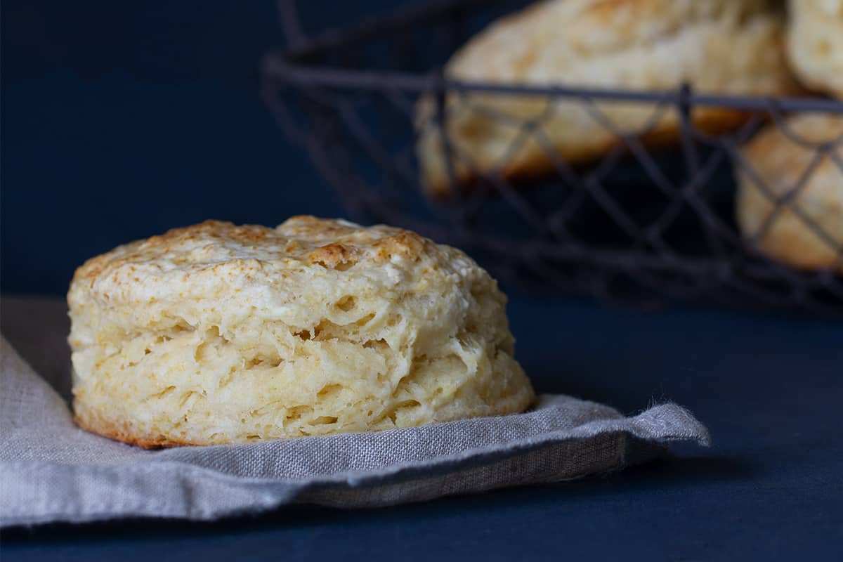 Close-up of a scone with a wire basket of scones in the background.