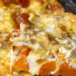 A slice of pumpkin quiche with feta being served.
