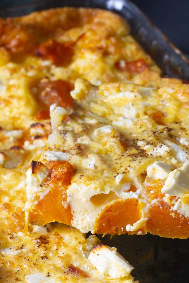 A slice of pumpkin quiche with feta being served.