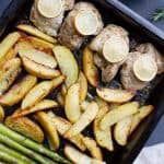 A sheet pan with chicken thighs, potatoes and asparagus.