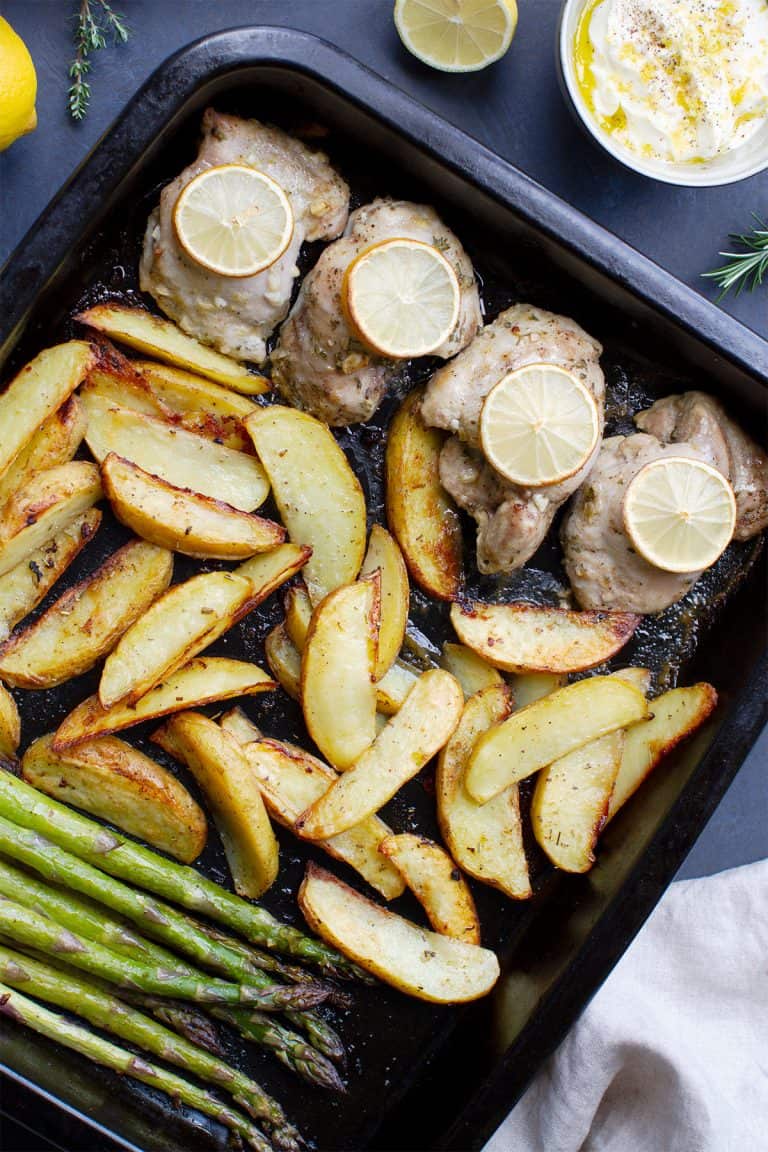 A sheet pan with chicken thighs, potatoes and asparagus.
