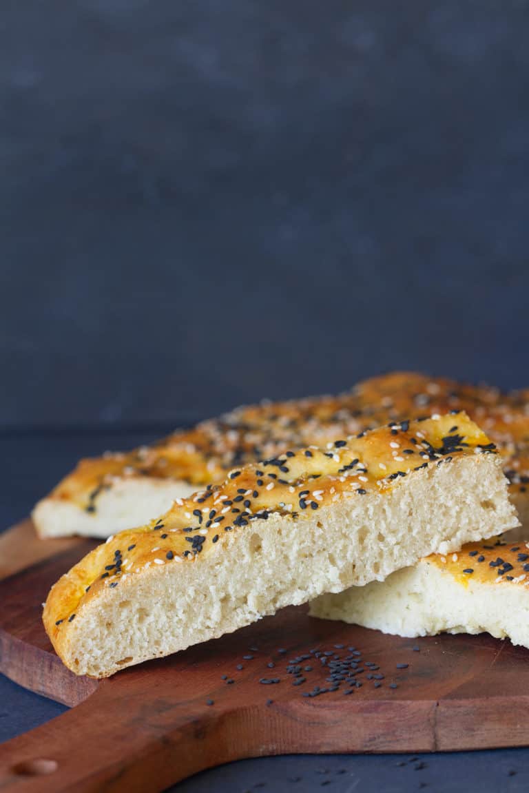 Small slices of Turkish pide bread on a round wooden board.