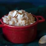 A red bowl of creamy rice pudding on a dark background.