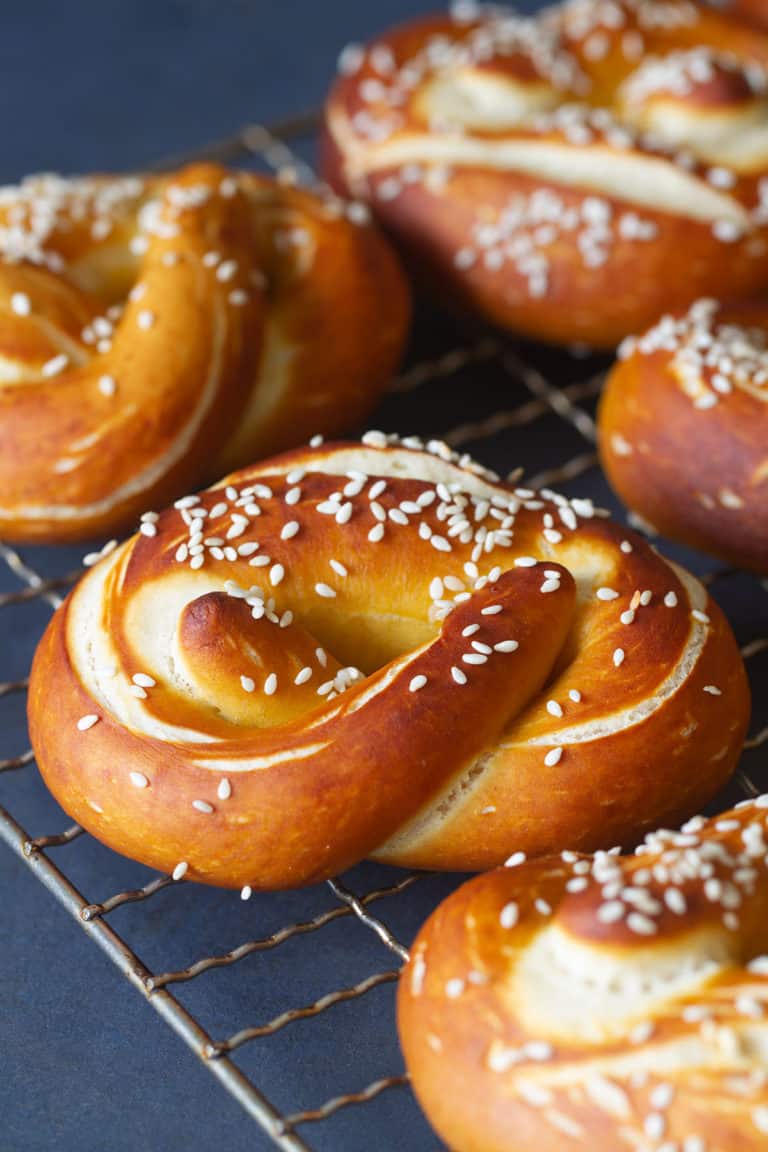A metal cookie tray with snack size soft German pretzels. Dark background.