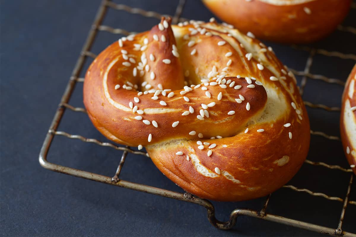 A metal cookie tray with snack size soft German pretzels. Dark background.