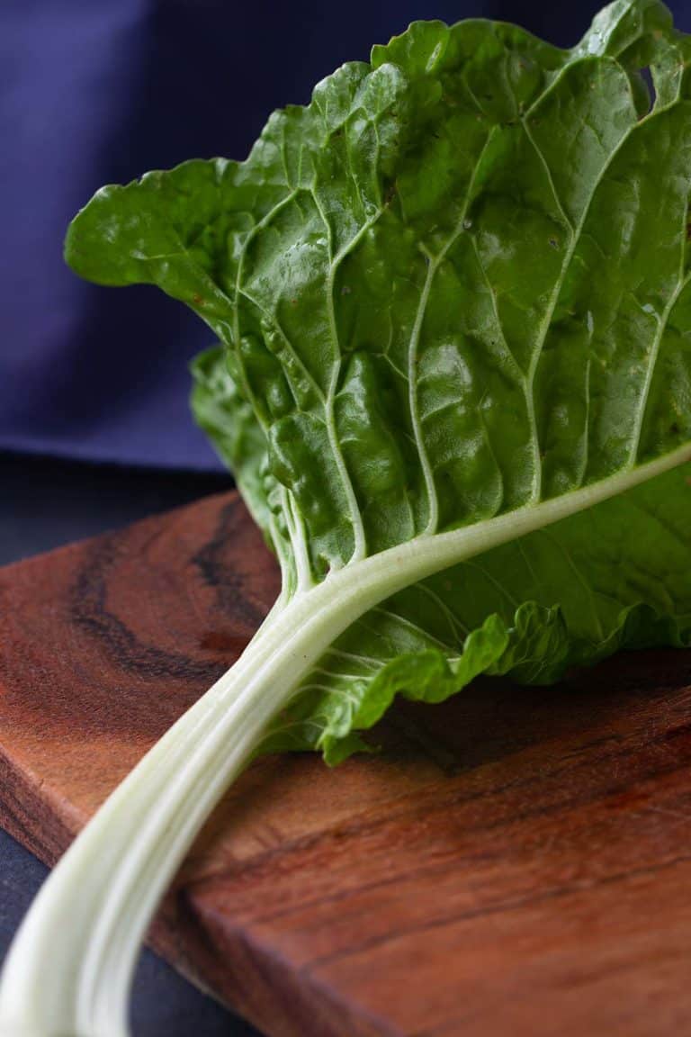 A stem of silverbeet on a wooden board.