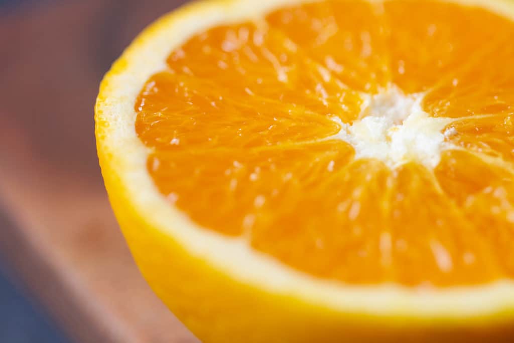 Close-up of half an orange on a wooden board.