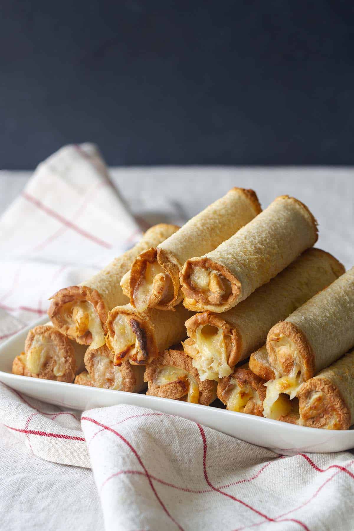 A stack of New Zealand cheese rolls on a white plate.