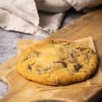 A chocolate chip cookie in a wooden board.