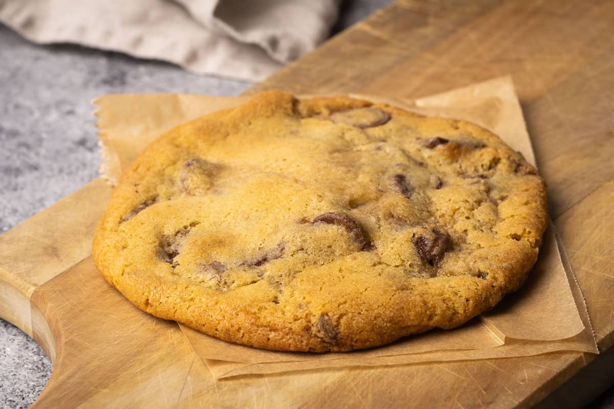 A chocolate chip cookie in a wooden board.