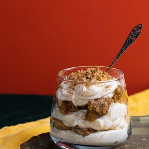 A chai tiramisu cup on a metal tray next to spices.
