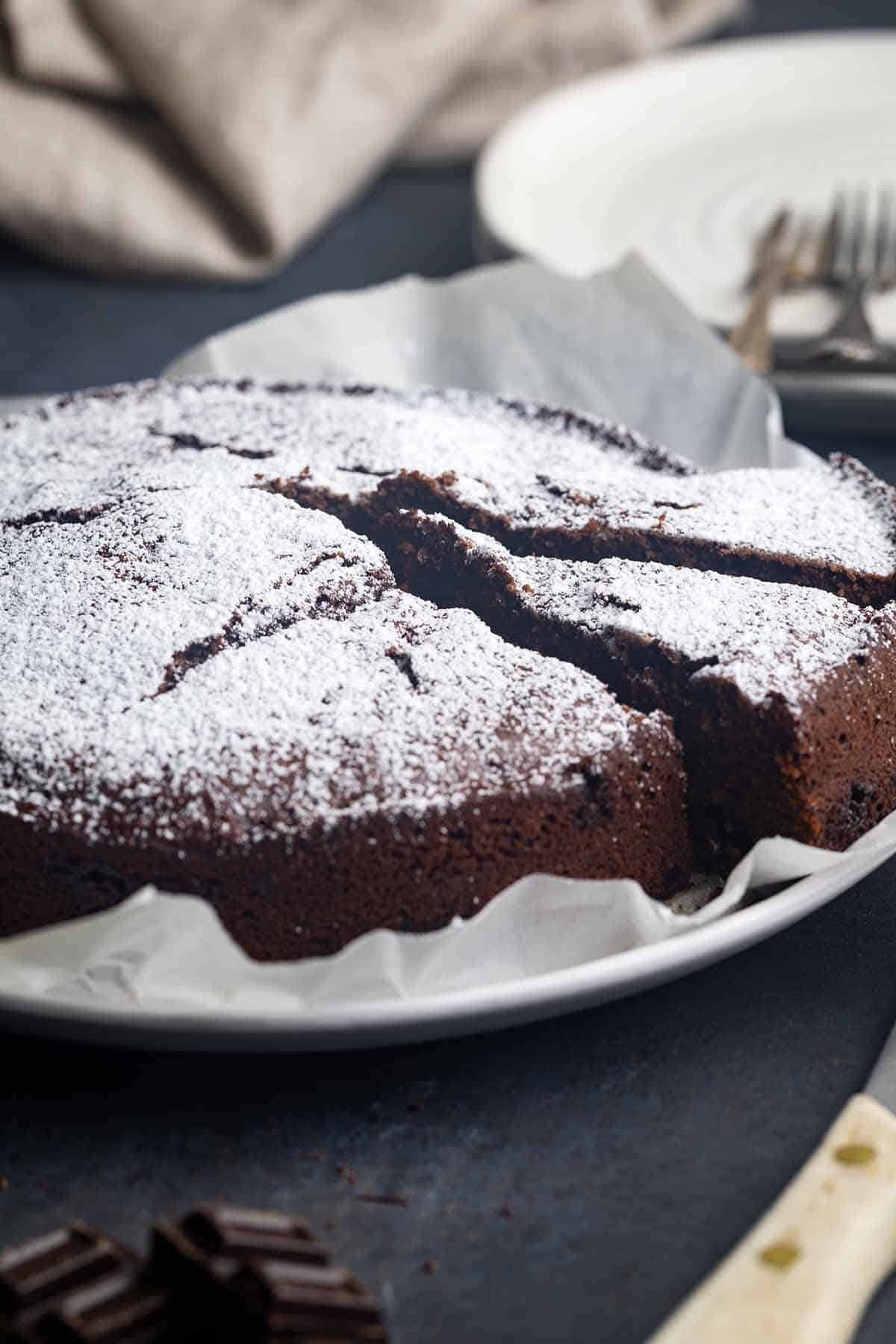 A sliced Schokokuchen on a plate. Plates in the back.