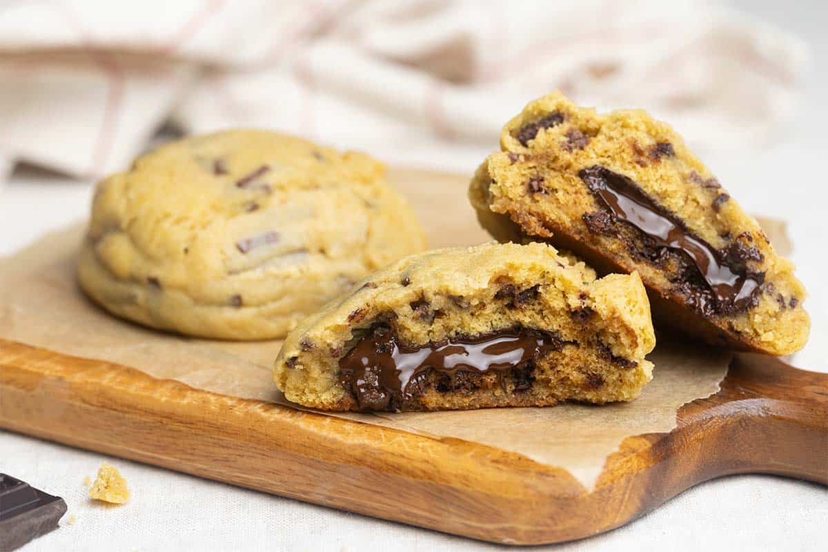 Two giant chocolate stuffed cookies on a wooden board.