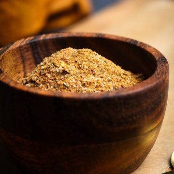 Homemade burrito seasoning in a wooden bowl on a wooden board.