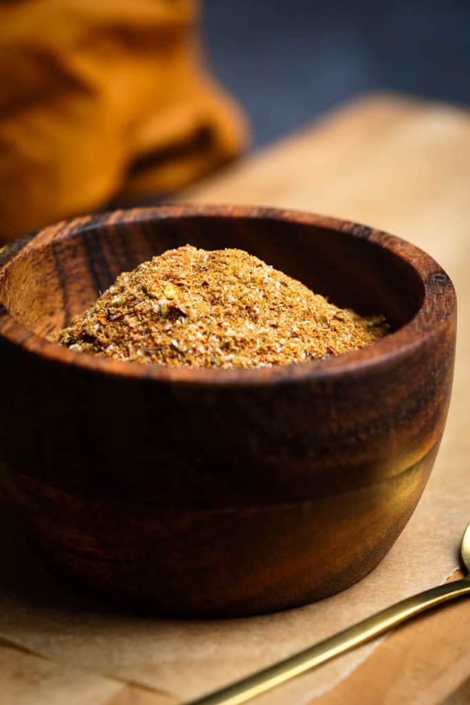 Homemade burrito seasoning in a wooden bowl on a wooden board.