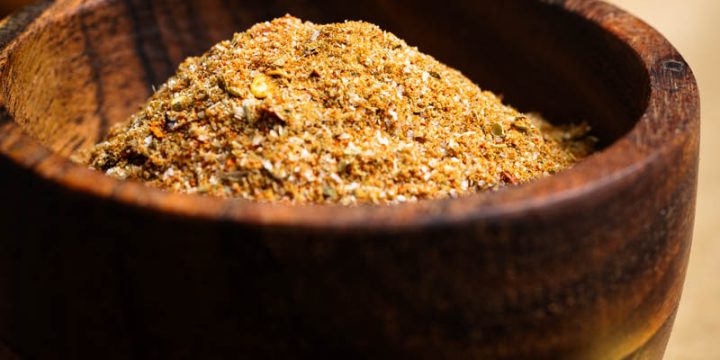 Homemade burrito seasoning in a wooden bowl on a wooden board.