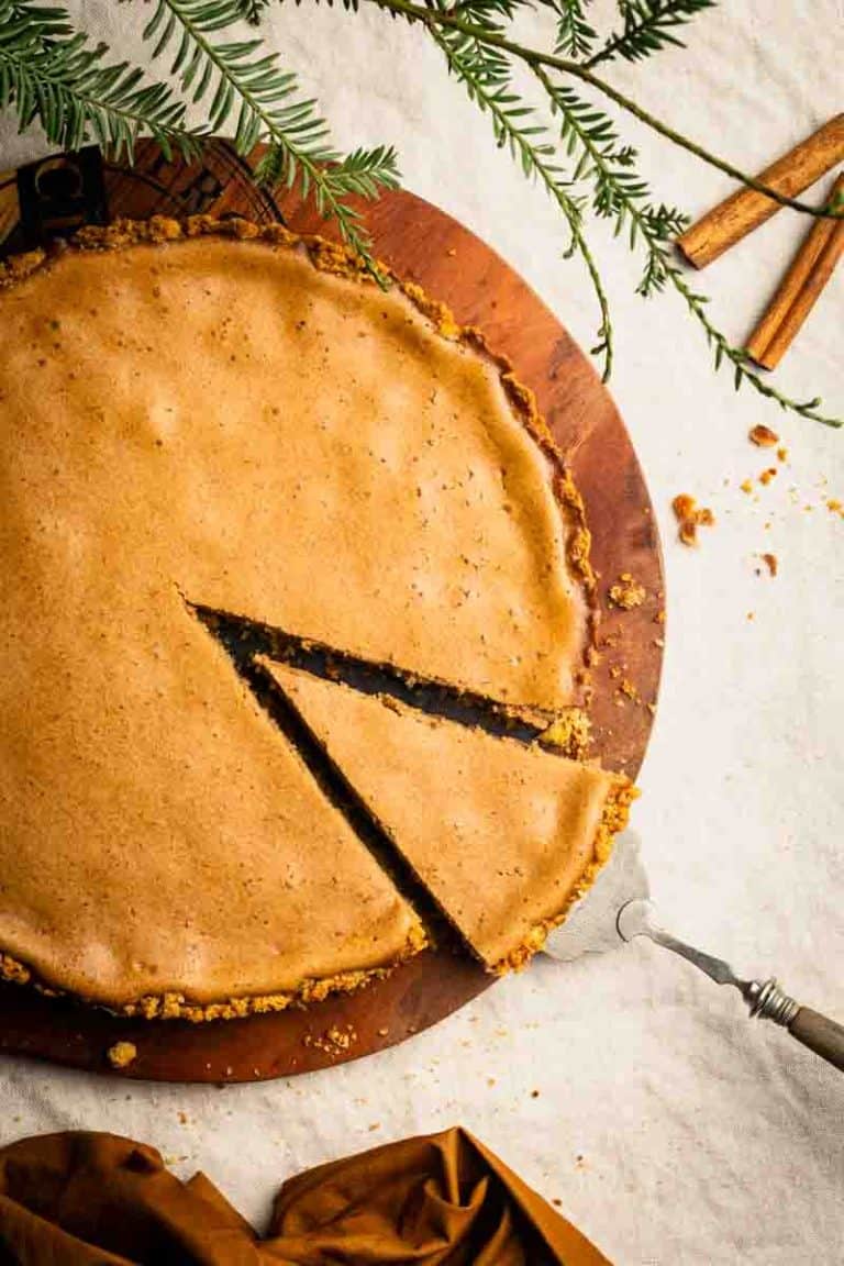 A slice being taken out of a cinnamon pie with pretzel crust. Fall-colored, cozy scene.