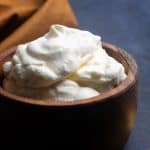 A wooden bowl filled with German whipped cream next to a golden spoon and napkin.