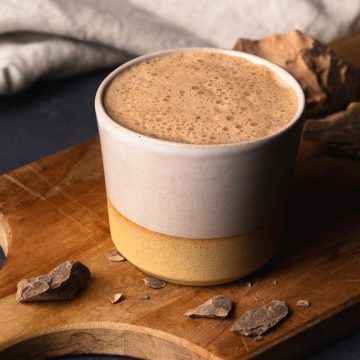 A cup of ceremonial cacao on a wooden board.