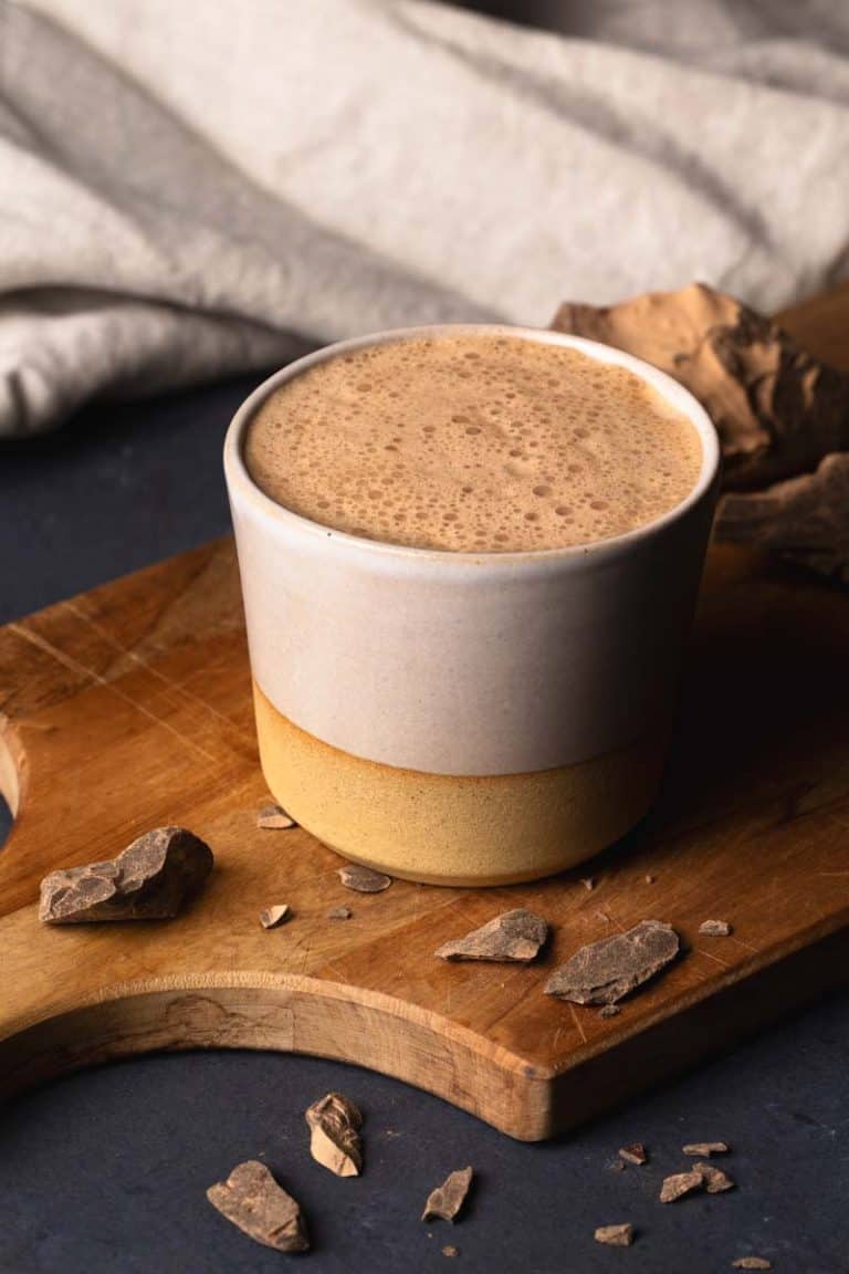 A cup of ceremonial cacao on a wooden board.