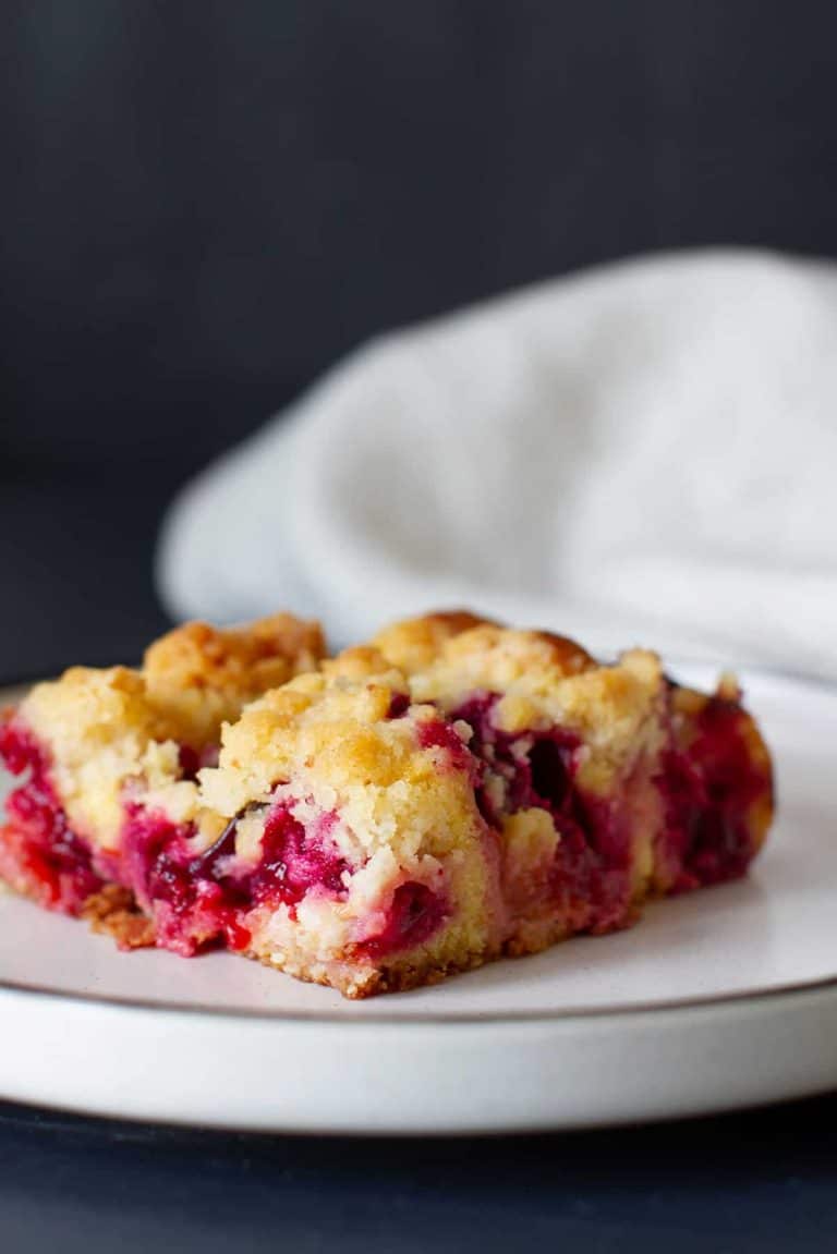 A piece of plum cake on a white plate.