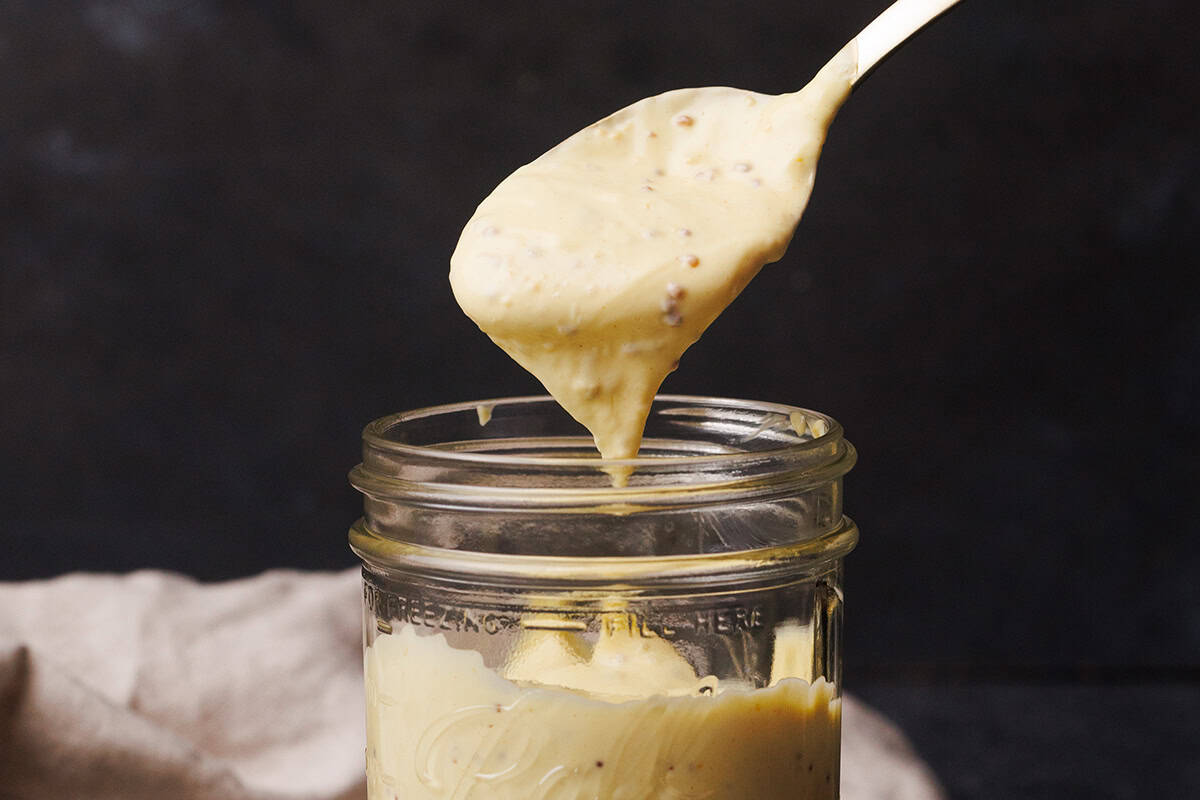 Dijonnaise on a spoon next to a jar.