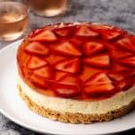 No-Bake Strawberry Cheesecake on a white plate next to Rosé glasses.