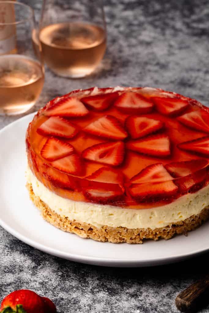No-Bake Strawberry Cheesecake on a white plate next to Rosé glasses.