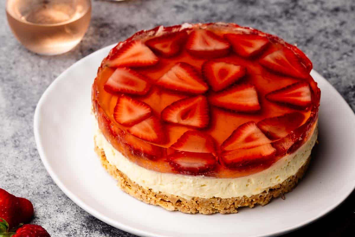No-Bake Strawberry Cheesecake on a white plate next to Rosé glasses.