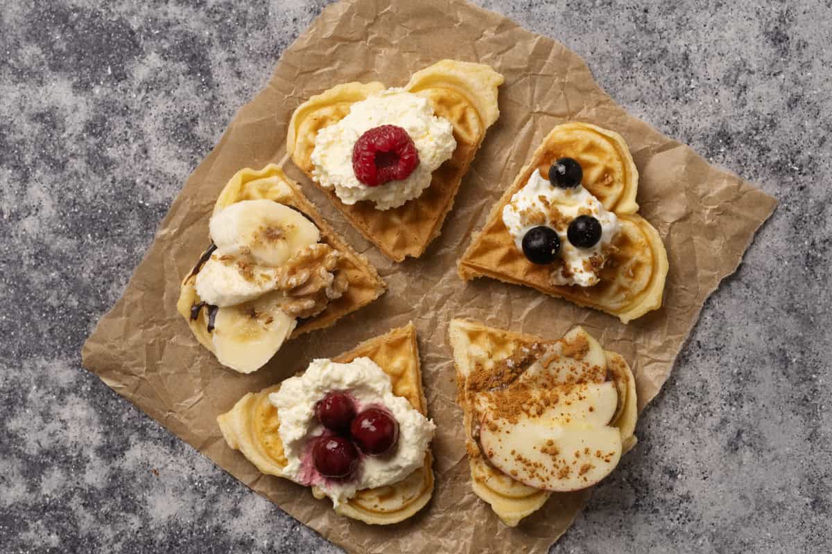 A waffle in 5 different pieces with different waffle toppings.