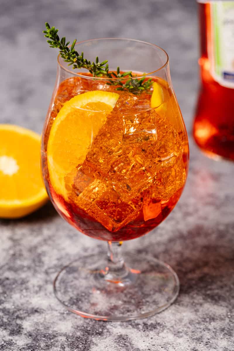 A Rosé Aperol Spritz Cocktail next to an Aperol bottle.