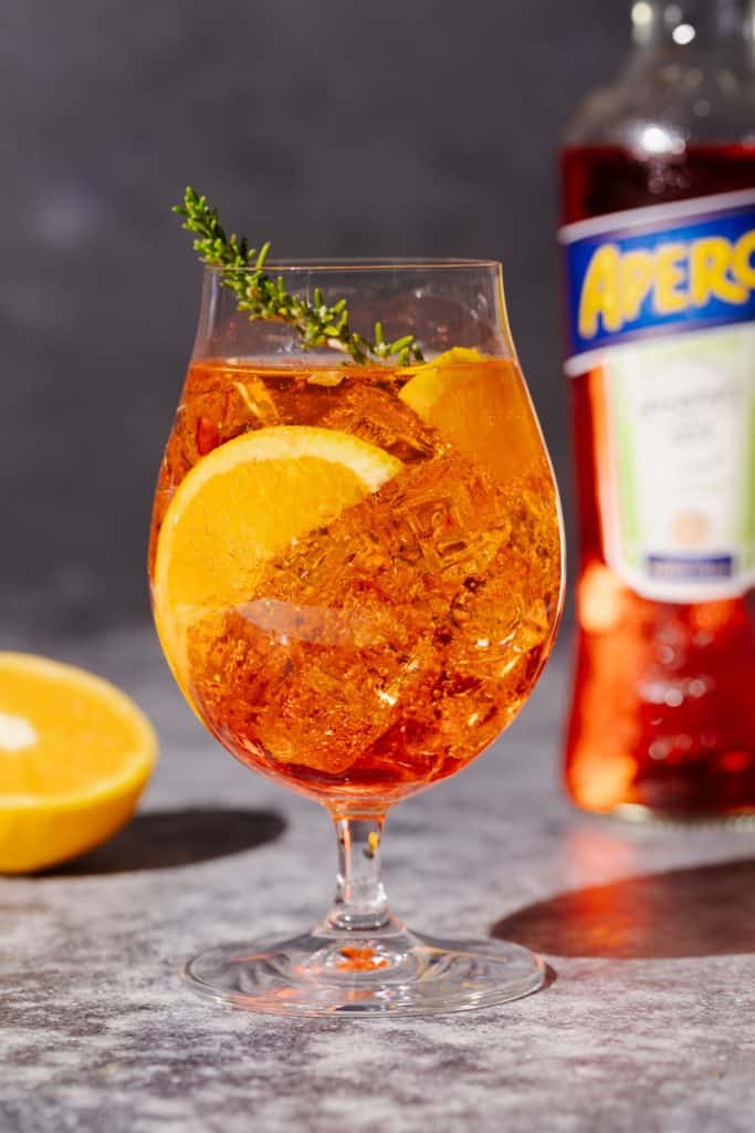 A Rosé Aperol Spritz Cocktail next to an Aperol bottle.