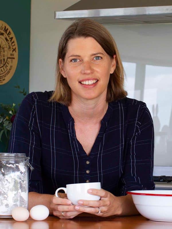 Caro Jensen from Caroha leaning on her kitchen counter holding a tea cup.