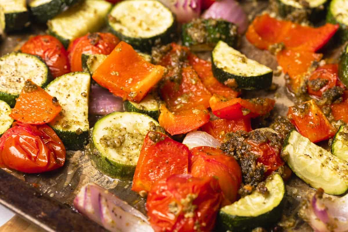 A large tray of pesto roasted vegetables next to a green napkin.