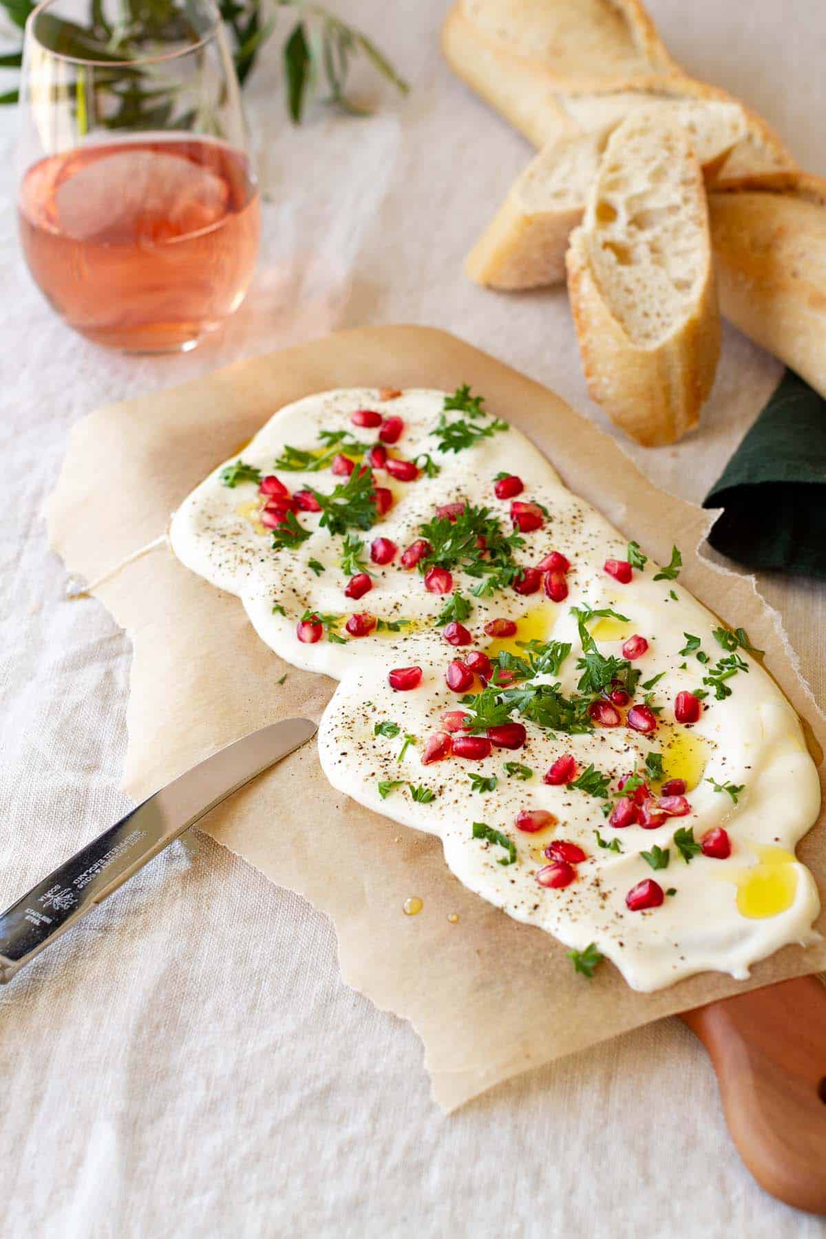 A whipped feta board next to Rosé wine glasses.