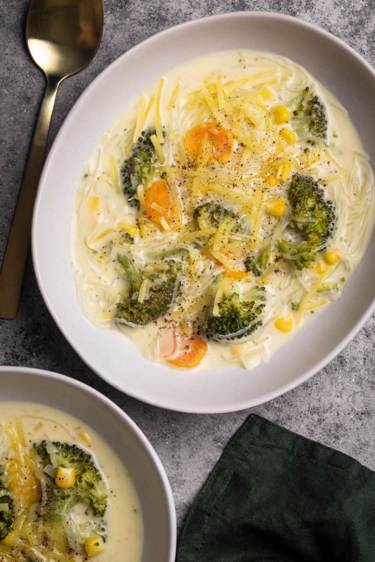 Two bowls filled with broccoli cheese soup with noodles.