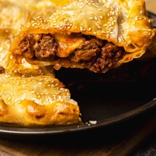 A slice of ground beef pie being lifted from the pie dish.