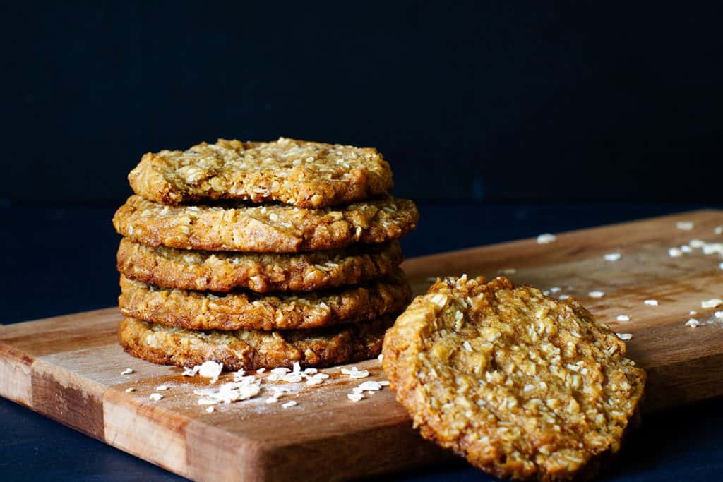 A stack of Anzac biscuits on a wooden board.