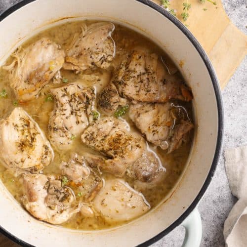 Cooked chicken thighs in a mint Dutch oven.