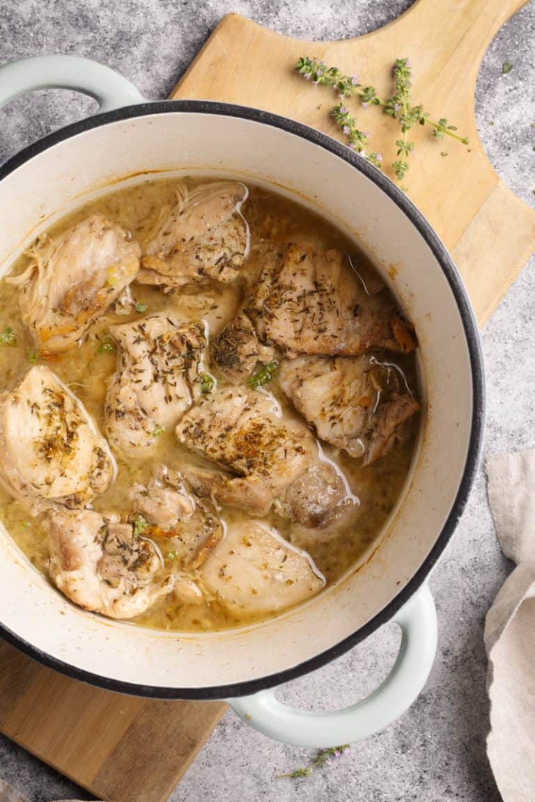 Cooked chicken thighs in a mint Dutch oven.