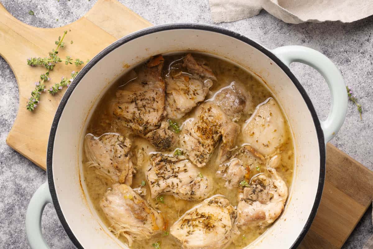 Cooked chicken thighs in a mint Dutch oven.