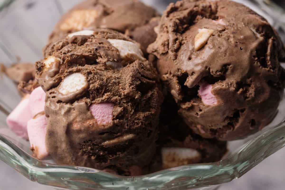 Three scoops of chocolate marshmallow ice cream in a dessert glass.