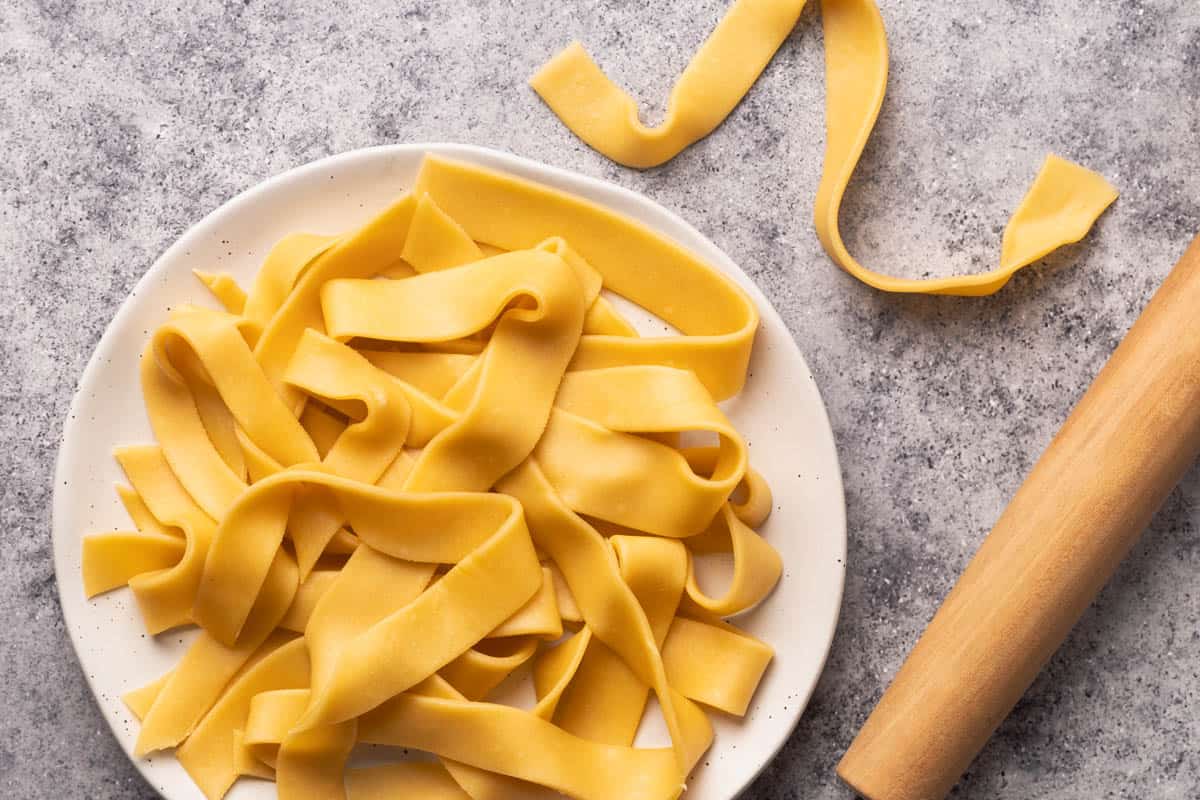 Fresh ribbon pasta on a white plate.
