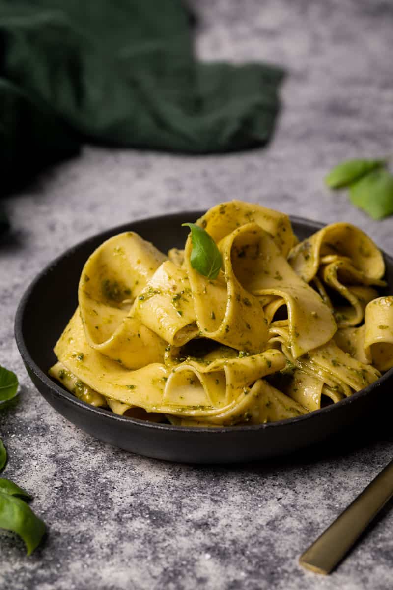 Pesto ribbon noodles on a black plate.