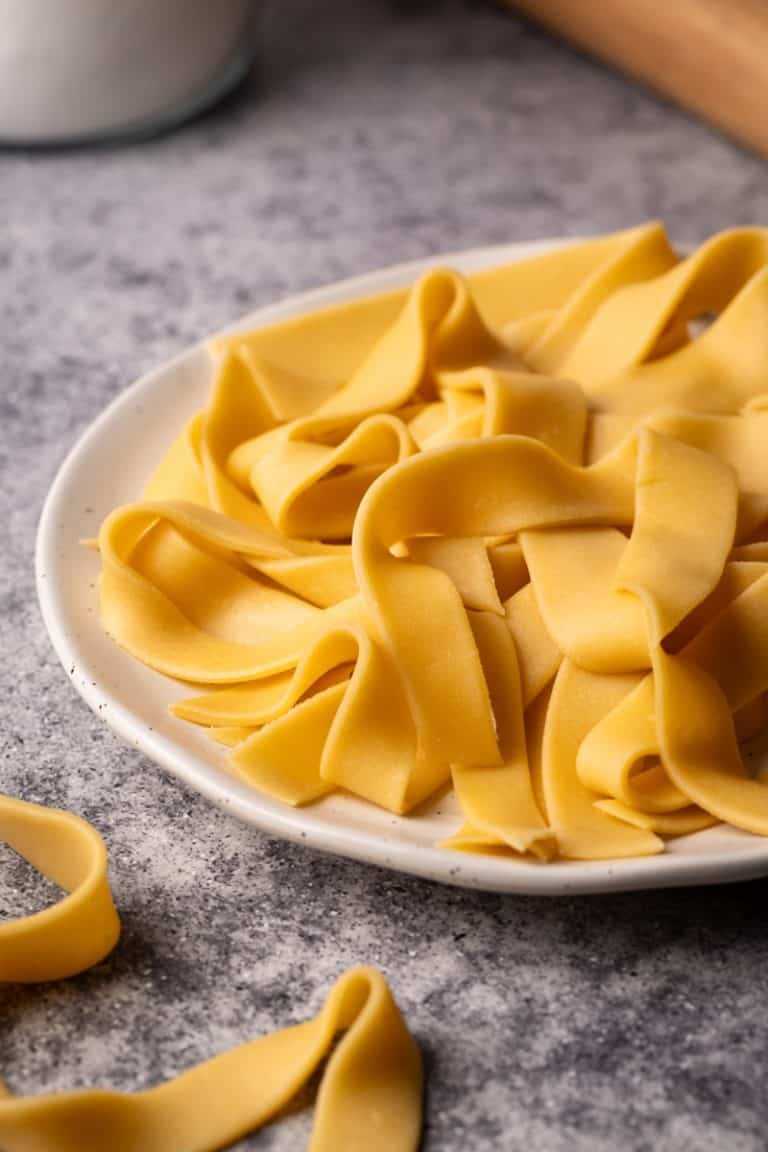 Fresh ribbon pasta on a white plate.